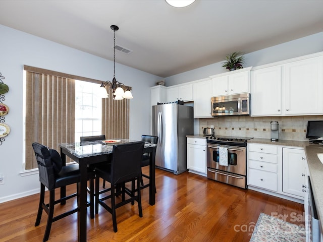 kitchen with dark wood finished floors, visible vents, decorative backsplash, appliances with stainless steel finishes, and white cabinetry