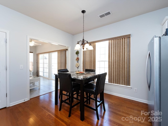 dining room with an inviting chandelier, baseboards, visible vents, and wood finished floors