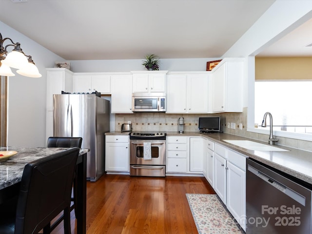 kitchen with stainless steel appliances, white cabinetry, a sink, and tasteful backsplash