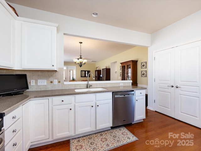 kitchen featuring backsplash, a peninsula, stainless steel dishwasher, white cabinetry, and a sink