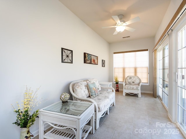 living area with visible vents, ceiling fan, baseboards, and light tile patterned floors