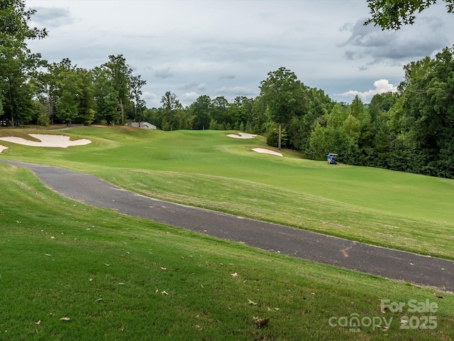 view of home's community featuring view of golf course and a yard