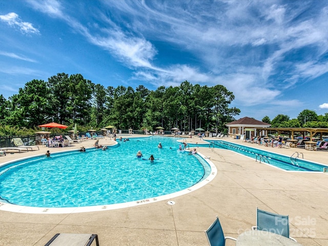 community pool with a patio area and fence