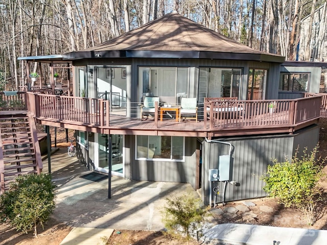 back of property with a wooden deck and a patio