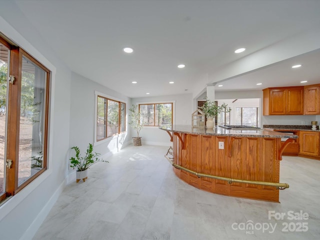 kitchen featuring a center island, stainless steel gas stovetop, a breakfast bar, and light stone countertops