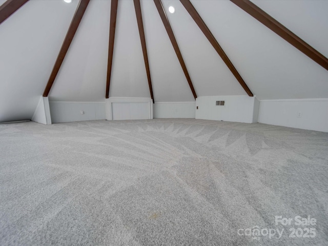 bonus room with lofted ceiling with beams and light carpet