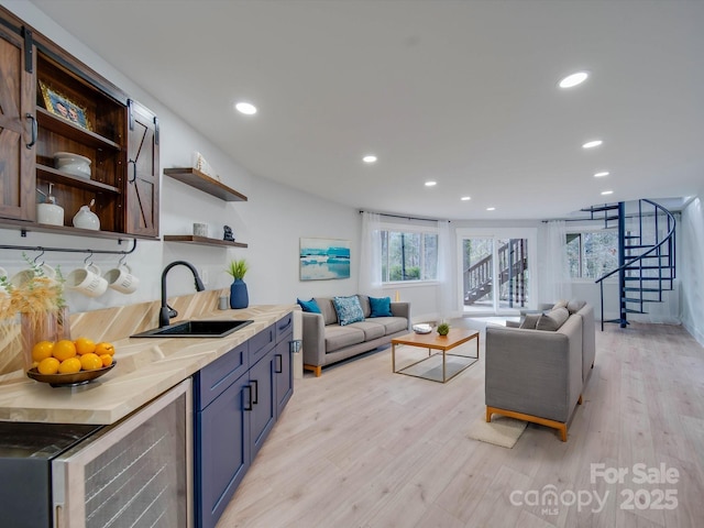 living room featuring beverage cooler, sink, and light hardwood / wood-style flooring