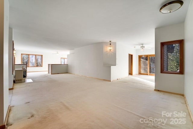 unfurnished room with plenty of natural light, light colored carpet, and ceiling fan