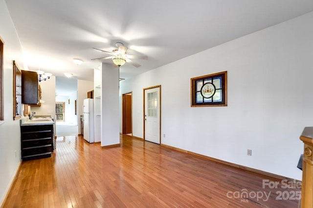 unfurnished living room featuring ceiling fan, sink, and light wood-type flooring