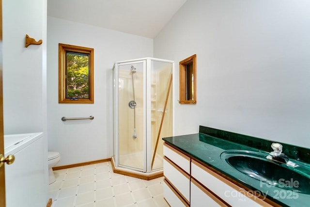 bathroom with vanity, washer / dryer, a shower with shower door, and toilet