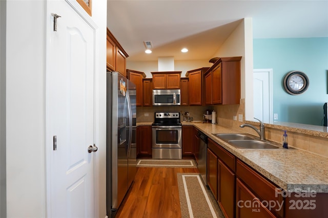 kitchen featuring sink, appliances with stainless steel finishes, dark hardwood / wood-style floors, tasteful backsplash, and kitchen peninsula