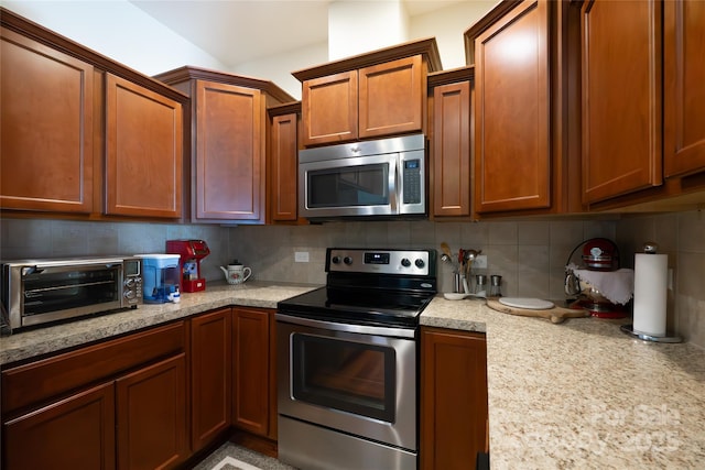 kitchen featuring stainless steel appliances, tasteful backsplash, and light stone counters