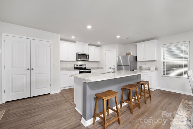 kitchen with sink, stainless steel appliances, an island with sink, and white cabinets