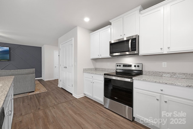 kitchen with white cabinetry, light stone counters, stainless steel appliances, and dark hardwood / wood-style floors