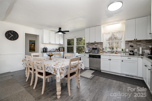 kitchen featuring sink, light stone countertops, white cabinets, dark hardwood / wood-style flooring, and stainless steel dishwasher