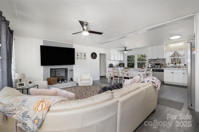 living room featuring hardwood / wood-style floors, sink, a textured ceiling, and ceiling fan