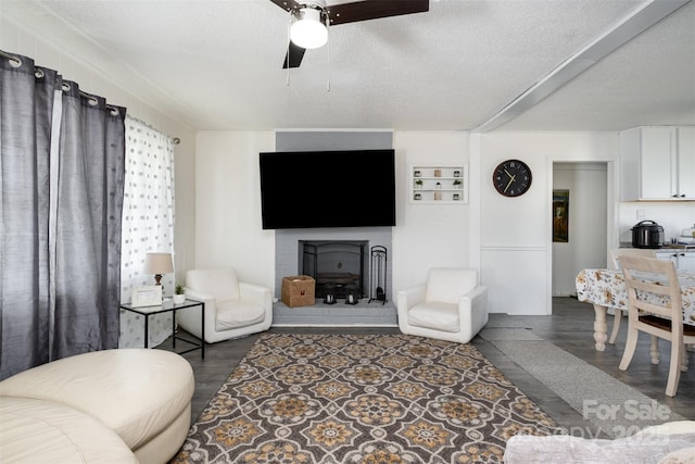 living room featuring ceiling fan, a textured ceiling, and dark hardwood / wood-style flooring