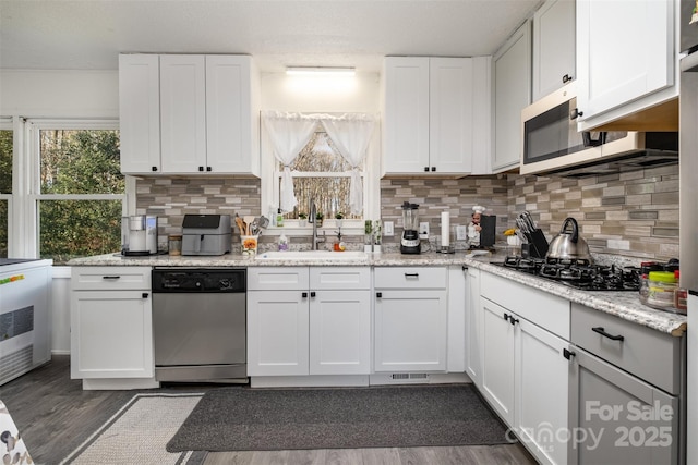 kitchen featuring white cabinetry, stainless steel appliances, sink, and light stone counters