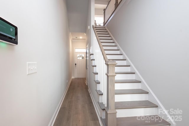 staircase with hardwood / wood-style floors and a towering ceiling