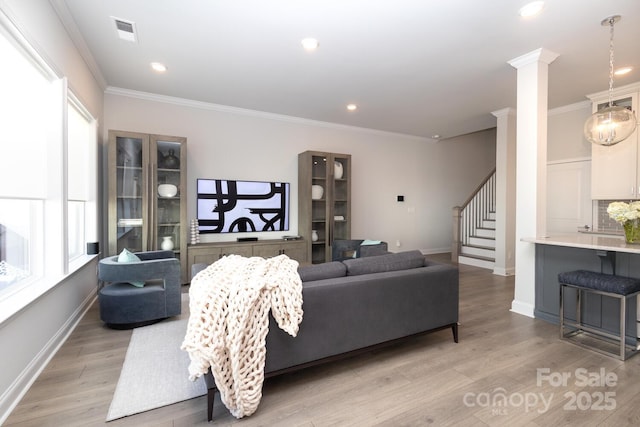 living room featuring ornamental molding, light hardwood / wood-style floors, and ornate columns