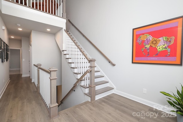 stairway with wood-type flooring and a high ceiling