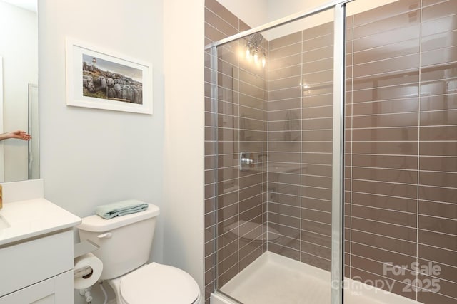 bathroom featuring vanity, toilet, and a shower with door