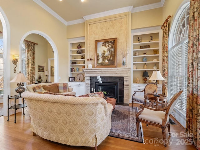 living room with ornamental molding, built in features, and light wood-type flooring