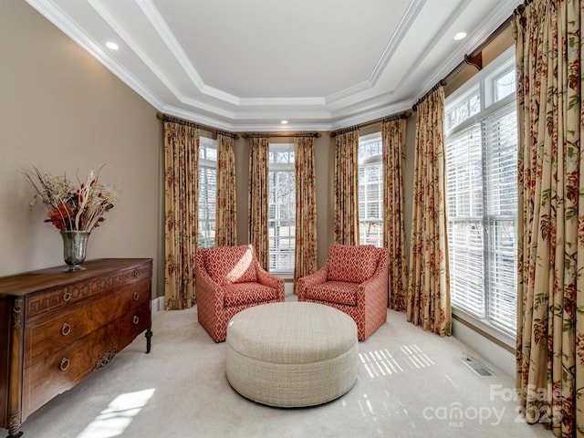 living area with a raised ceiling, ornamental molding, and light colored carpet