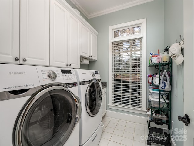 washroom with light tile patterned floors, crown molding, washer and clothes dryer, and cabinets