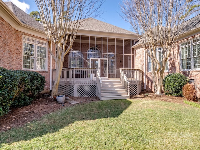 rear view of house with a yard, a deck, and a sunroom