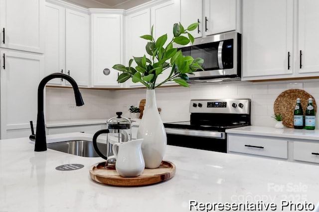 kitchen featuring light stone countertops, white cabinetry, appliances with stainless steel finishes, and decorative backsplash