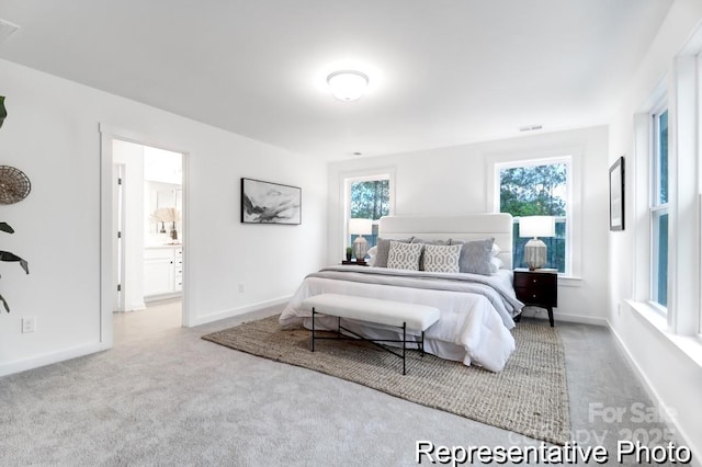 bedroom with light carpet and connected bathroom