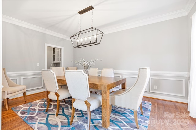 dining space with wood-type flooring, ornamental molding, and a chandelier