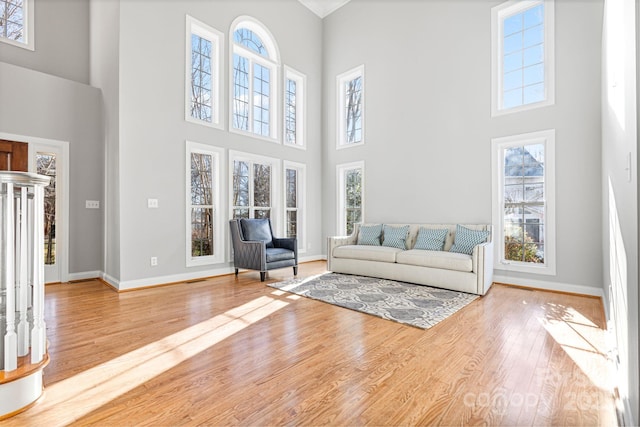 unfurnished living room with a wealth of natural light, light hardwood / wood-style flooring, and a high ceiling