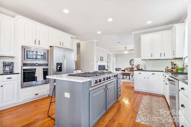 kitchen with gray cabinets, appliances with stainless steel finishes, a breakfast bar area, white cabinets, and a center island