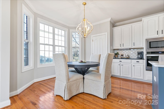 dining space featuring crown molding, an inviting chandelier, and light hardwood / wood-style flooring