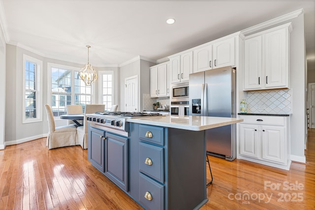 kitchen with blue cabinets, appliances with stainless steel finishes, white cabinets, and decorative light fixtures