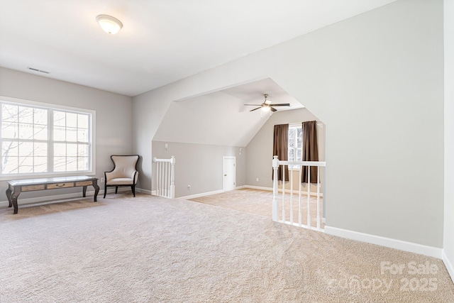 bonus room with vaulted ceiling, plenty of natural light, and light colored carpet