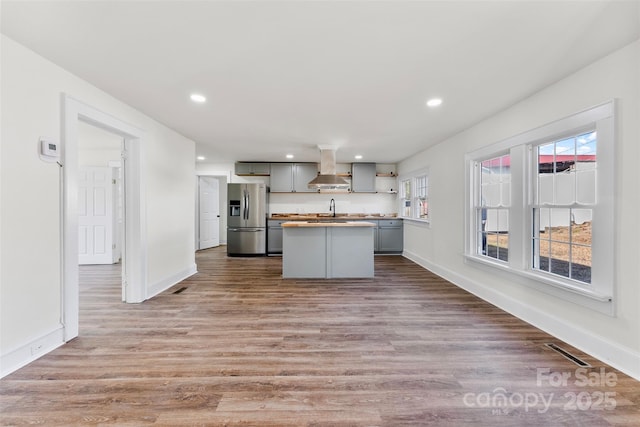 kitchen with stainless steel refrigerator with ice dispenser, sink, gray cabinetry, range hood, and light hardwood / wood-style floors