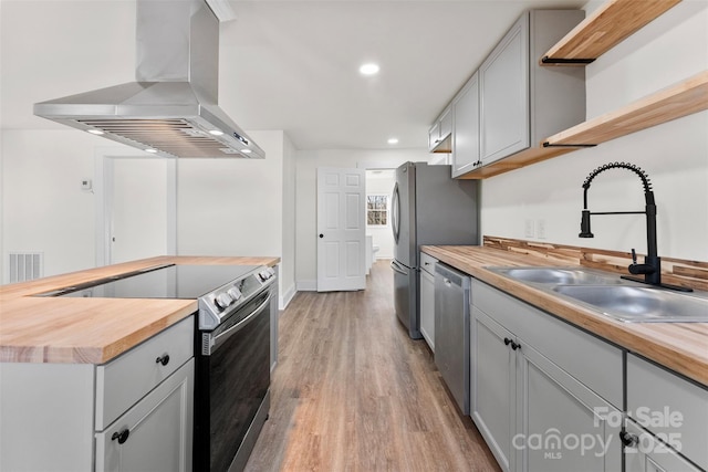 kitchen featuring gray cabinets, appliances with stainless steel finishes, butcher block counters, sink, and island exhaust hood