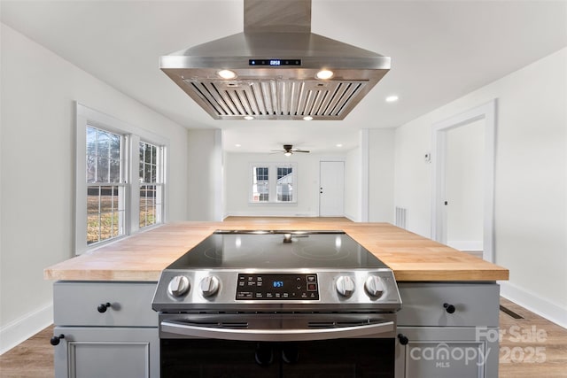 kitchen featuring butcher block counters, gray cabinets, stainless steel range with electric cooktop, and island exhaust hood