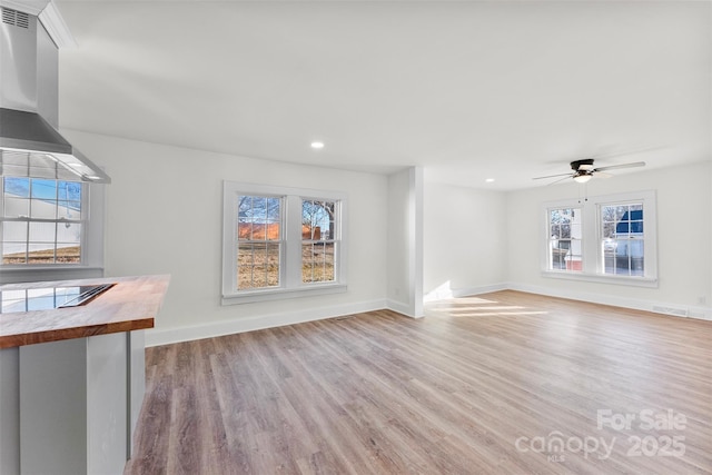 unfurnished living room with ceiling fan, light hardwood / wood-style flooring, and a healthy amount of sunlight