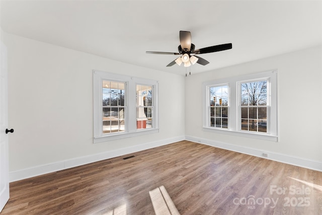 spare room with ceiling fan, plenty of natural light, and wood-type flooring