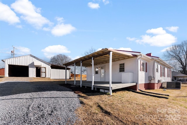 view of front of house with an outbuilding, a garage, central AC unit, a carport, and a front lawn