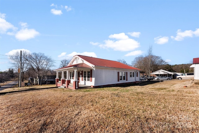 view of side of property featuring covered porch and a lawn