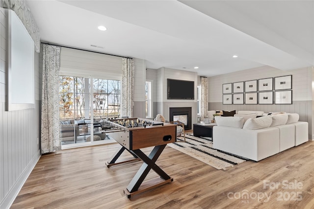 recreation room featuring light wood-type flooring and wood walls