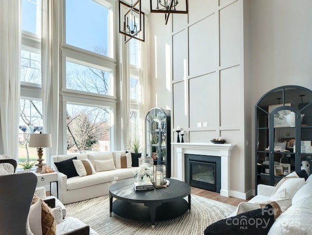 living room with an inviting chandelier, a towering ceiling, and light hardwood / wood-style floors