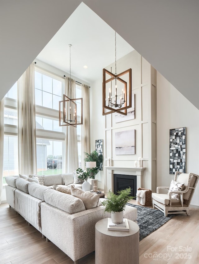 living room with a high ceiling, an inviting chandelier, and light hardwood / wood-style floors