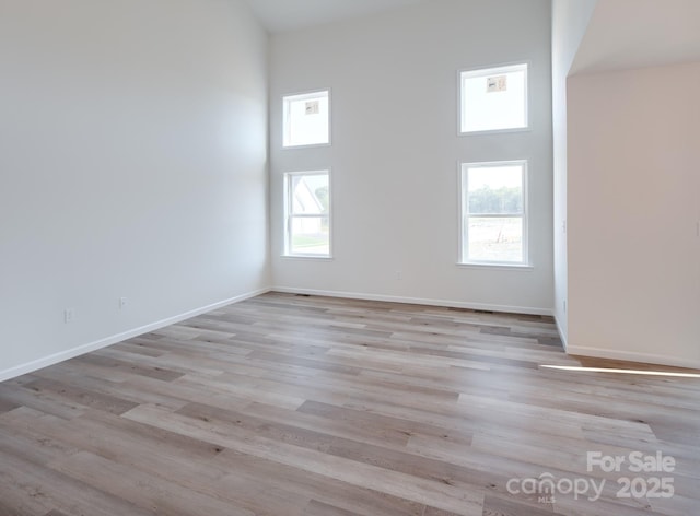 unfurnished room featuring a high ceiling and light hardwood / wood-style floors