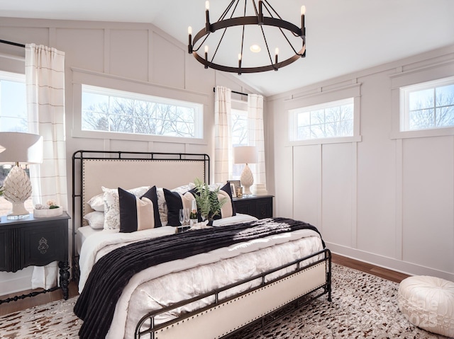 bedroom featuring lofted ceiling, hardwood / wood-style floors, and a notable chandelier